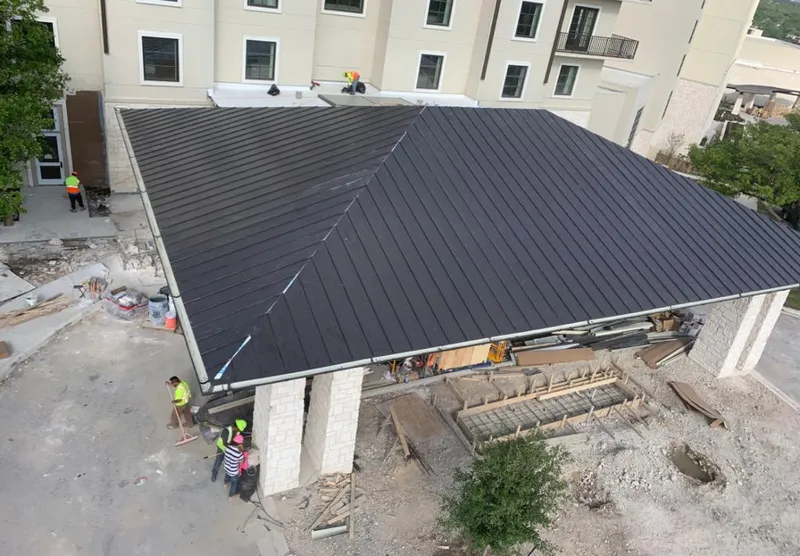 Metal roofing installation team working on a commercial building in Malone